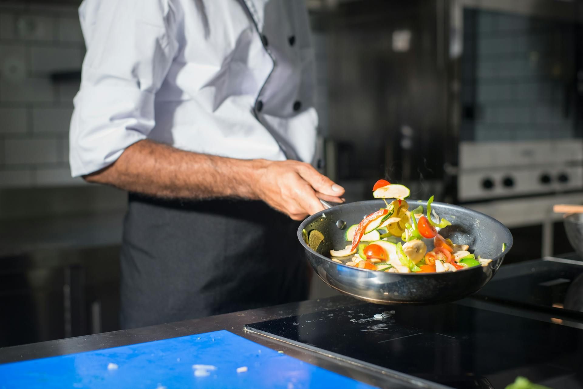 chef cocinando verduras en una sartén