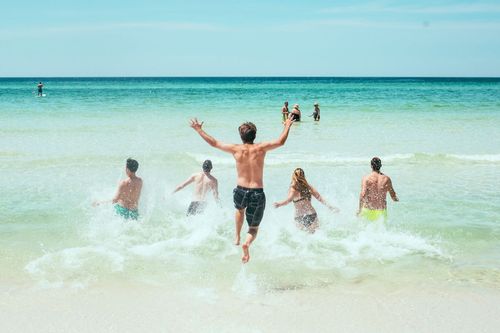 Junge Menschen springen im Sommer ins Meer